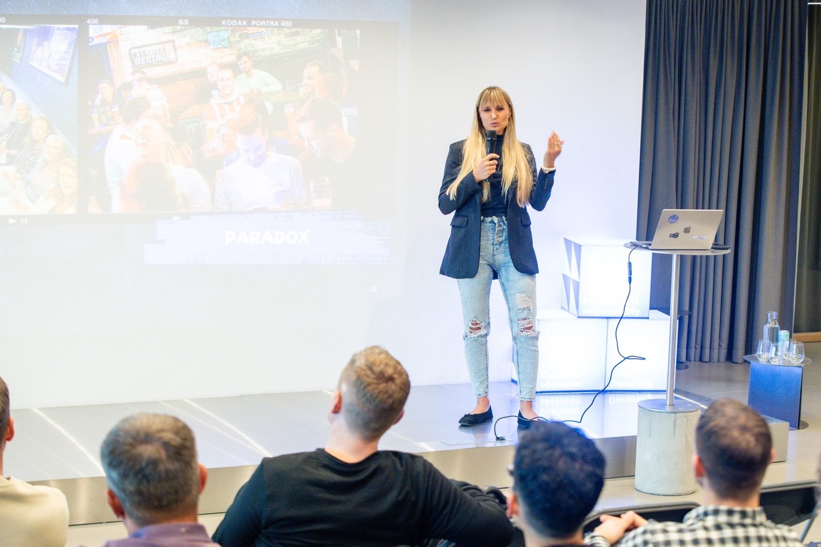 Odeta kalba scenoje 00AI meetup #7 susitikime Kaune, už jos skaidrė su užrašu „Paradox“.