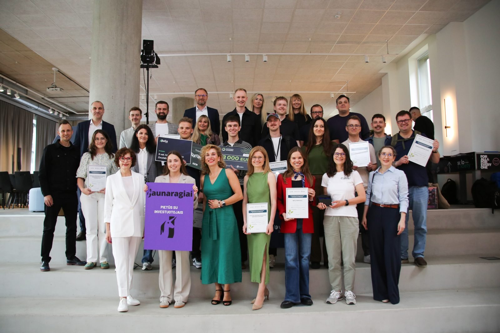 The Skaitmeninis knygnešys 2025 winners holding their diplomas in a group photo with Odeta after the awards.